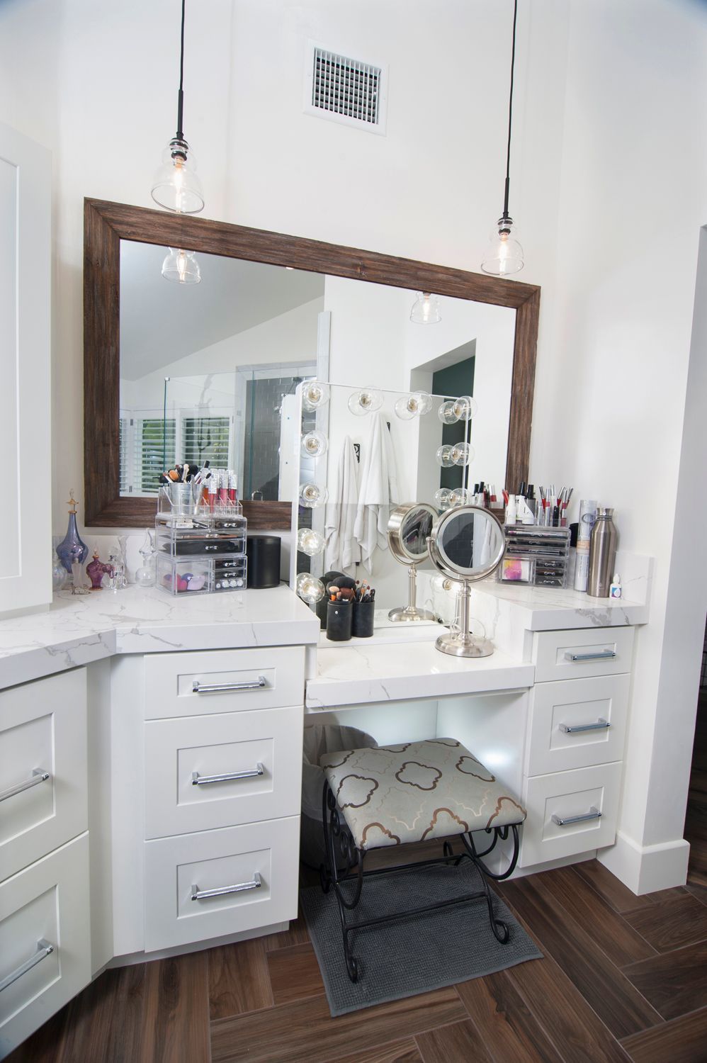 White vanity with a large mirror and makeup, stool, and drawers. Brown wood frame.