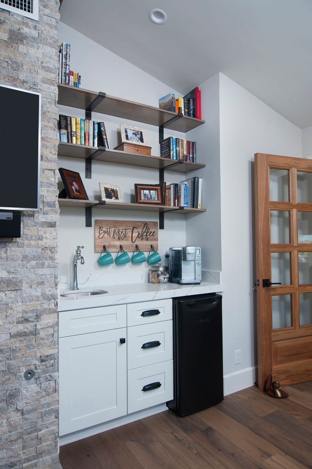 Home coffee bar with open shelving, white cabinets, and small refrigerator.