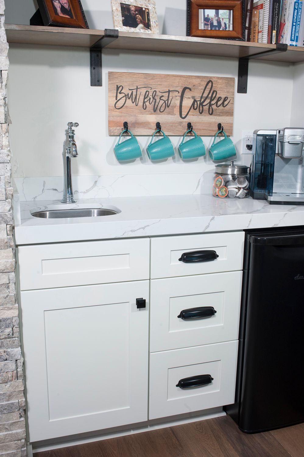 A white coffee bar with a sink, cabinets, and turquoise mugs; 