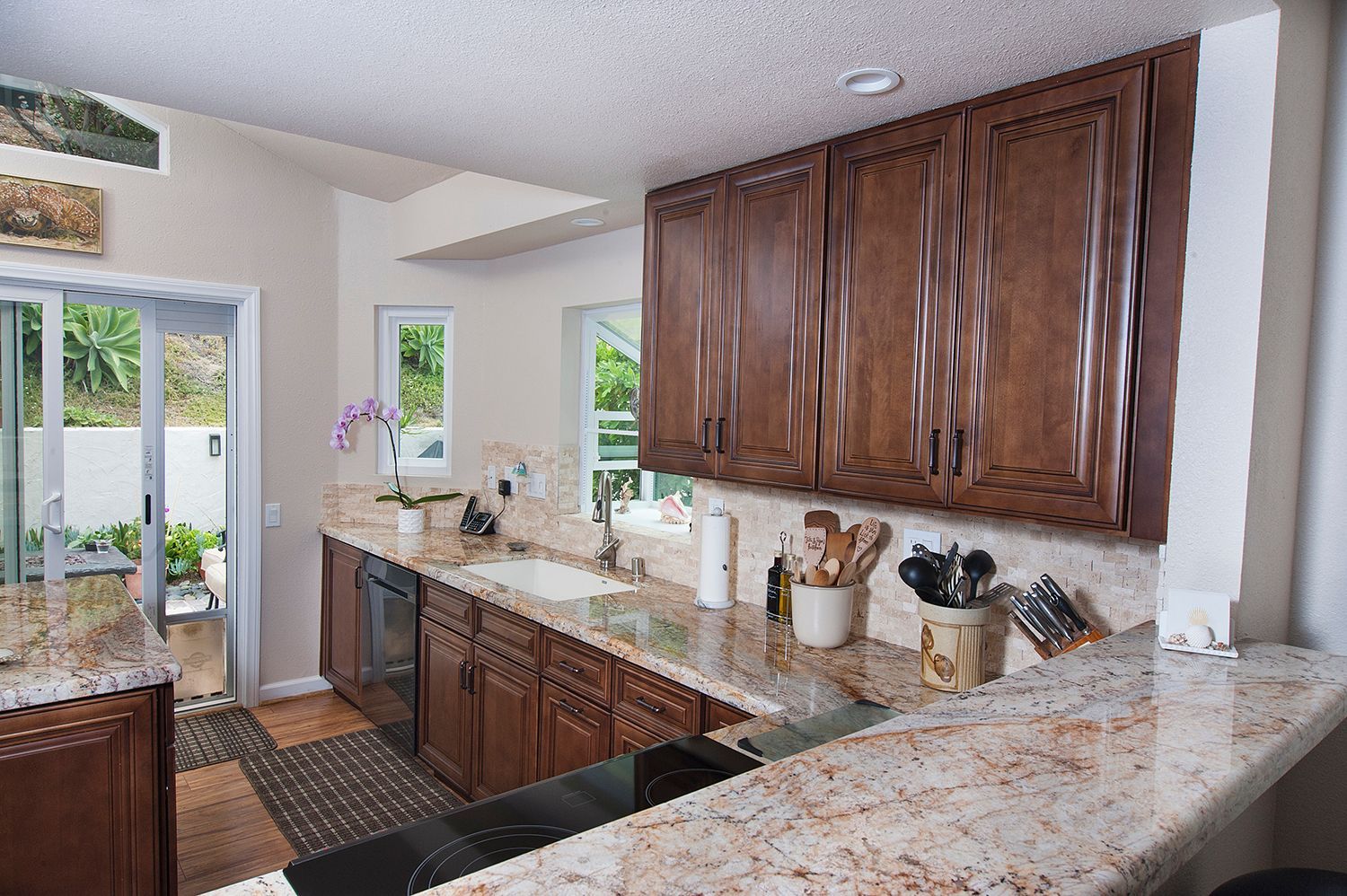 Kitchen with brown cabinets, granite countertops, and a view of a patio.