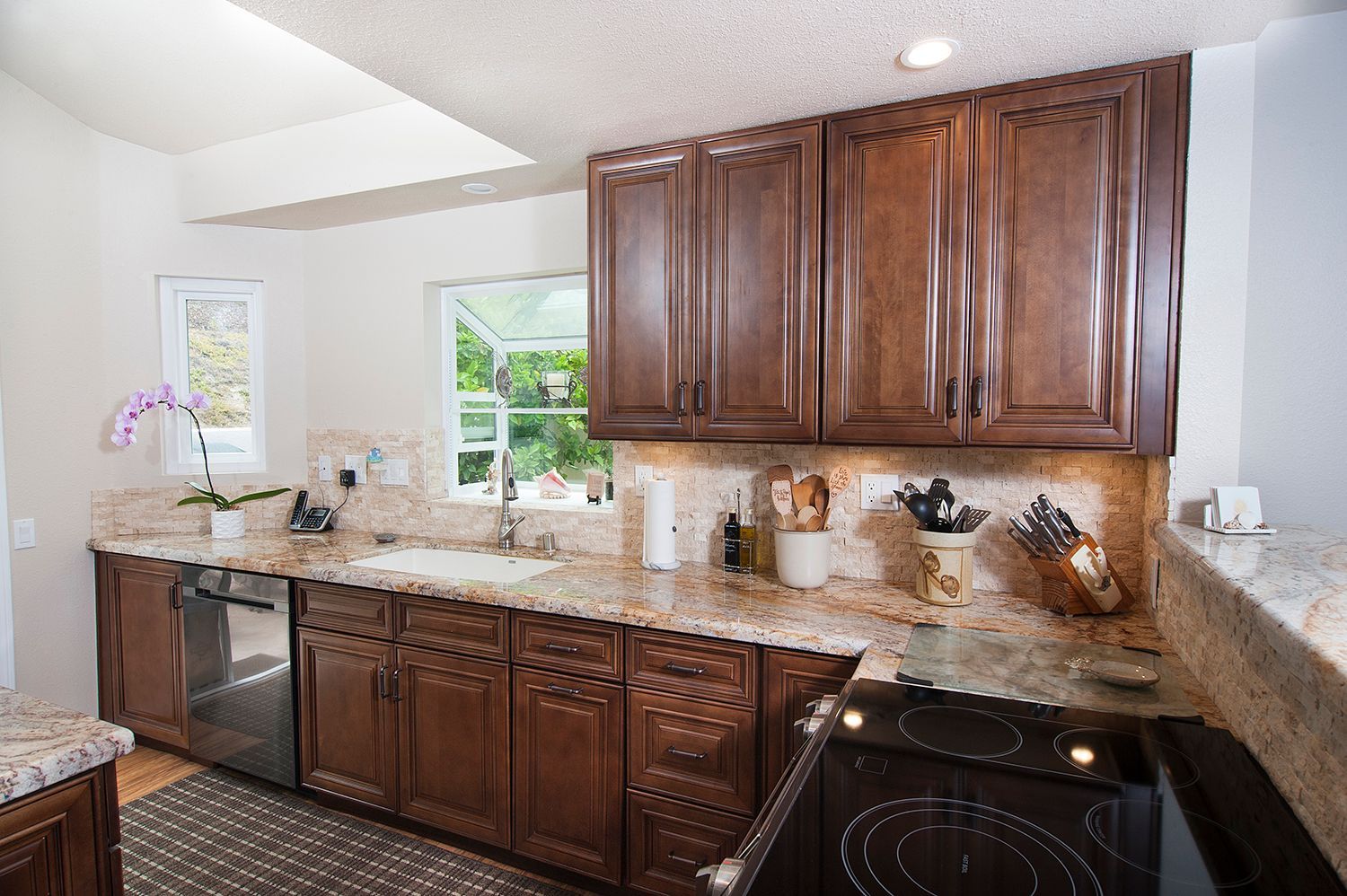 Kitchen with brown cabinets, granite countertops, and a dishwasher.