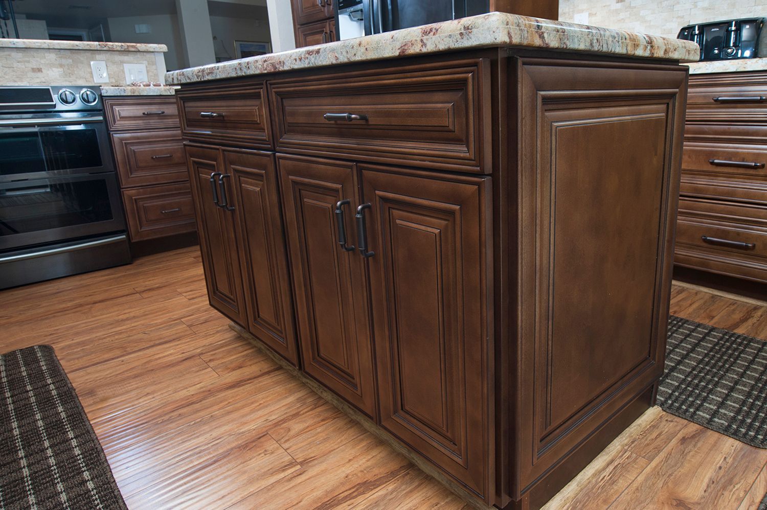 Dark brown kitchen island with granite countertop, set on wood floor.
