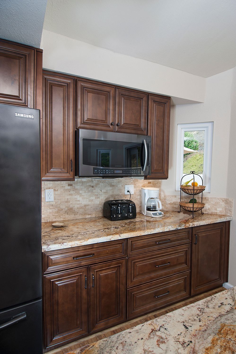Brown kitchen cabinets and granite countertop with a microwave, toaster, and coffee maker.