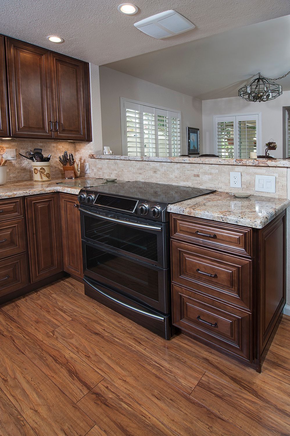 Dark wood kitchen with stove, cabinets, and granite countertops.