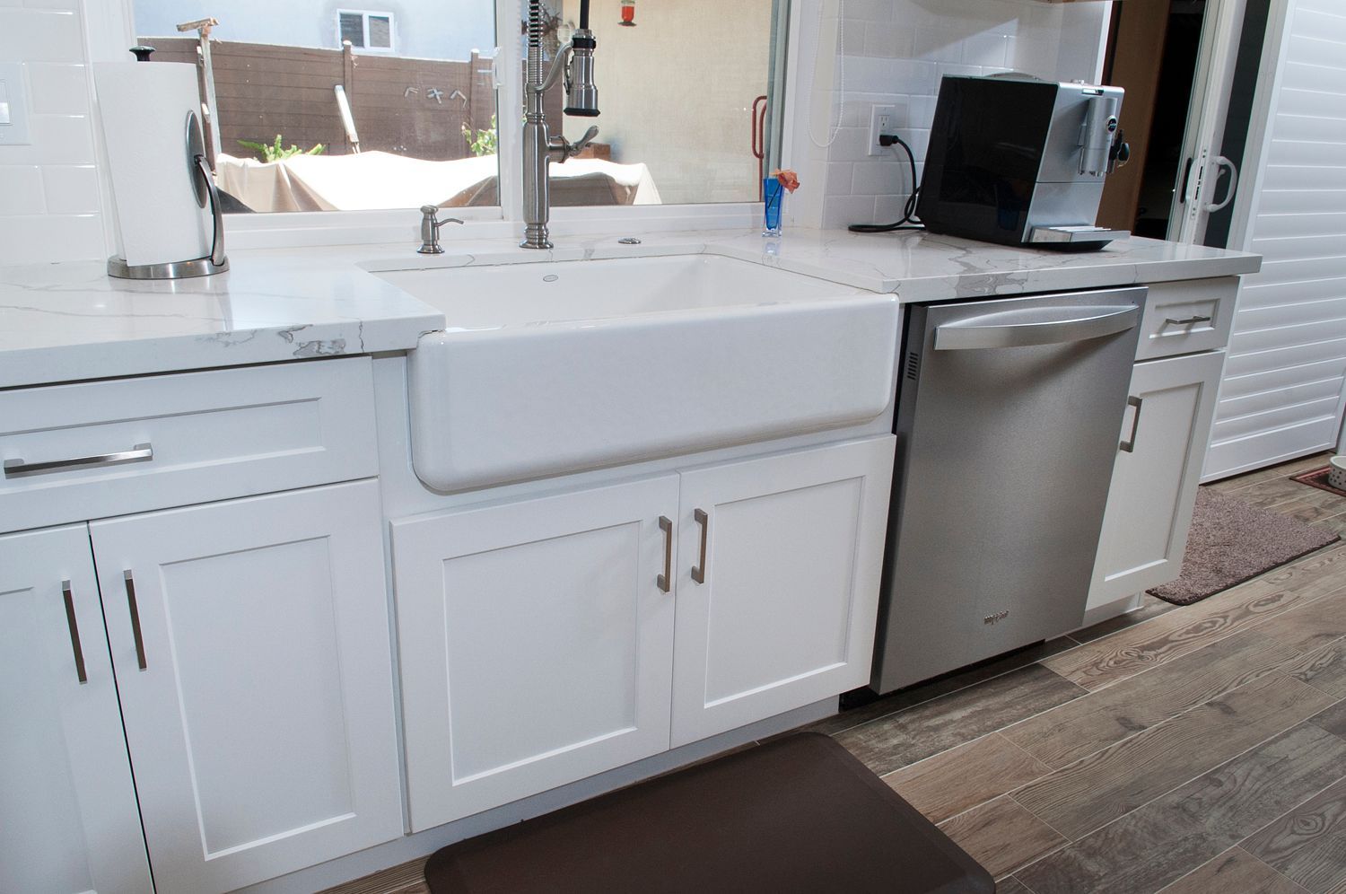 White farmhouse kitchen sink with stainless steel appliances.