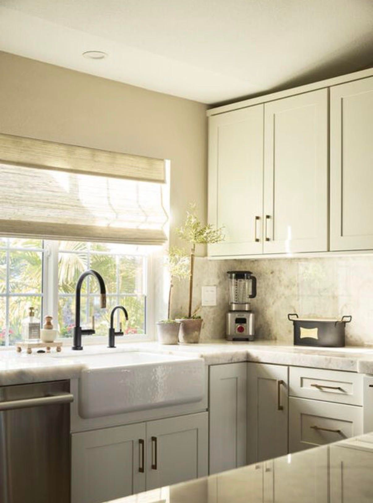 Kitchen with white cabinets, farmhouse sink, black faucet, and window with outdoor view.
