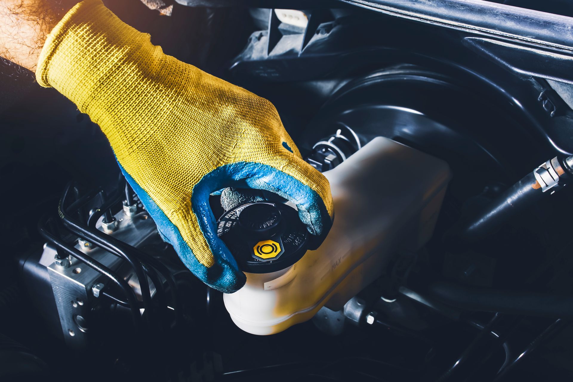 Gloved hand opening brake fluid reservoir under car hood