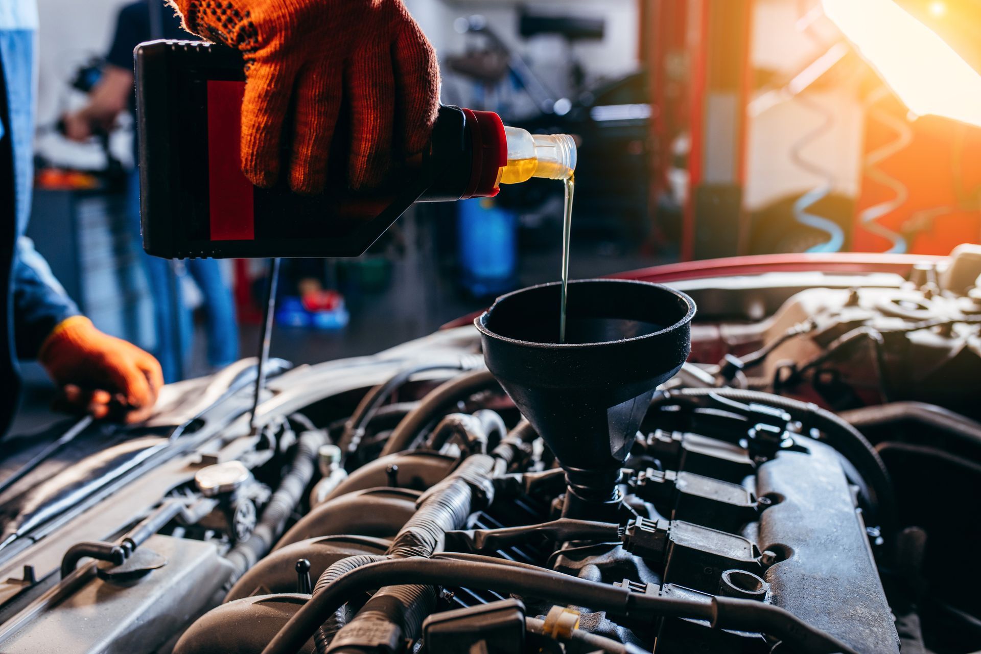 Mechanic pouring oil into a car engine using a funnel