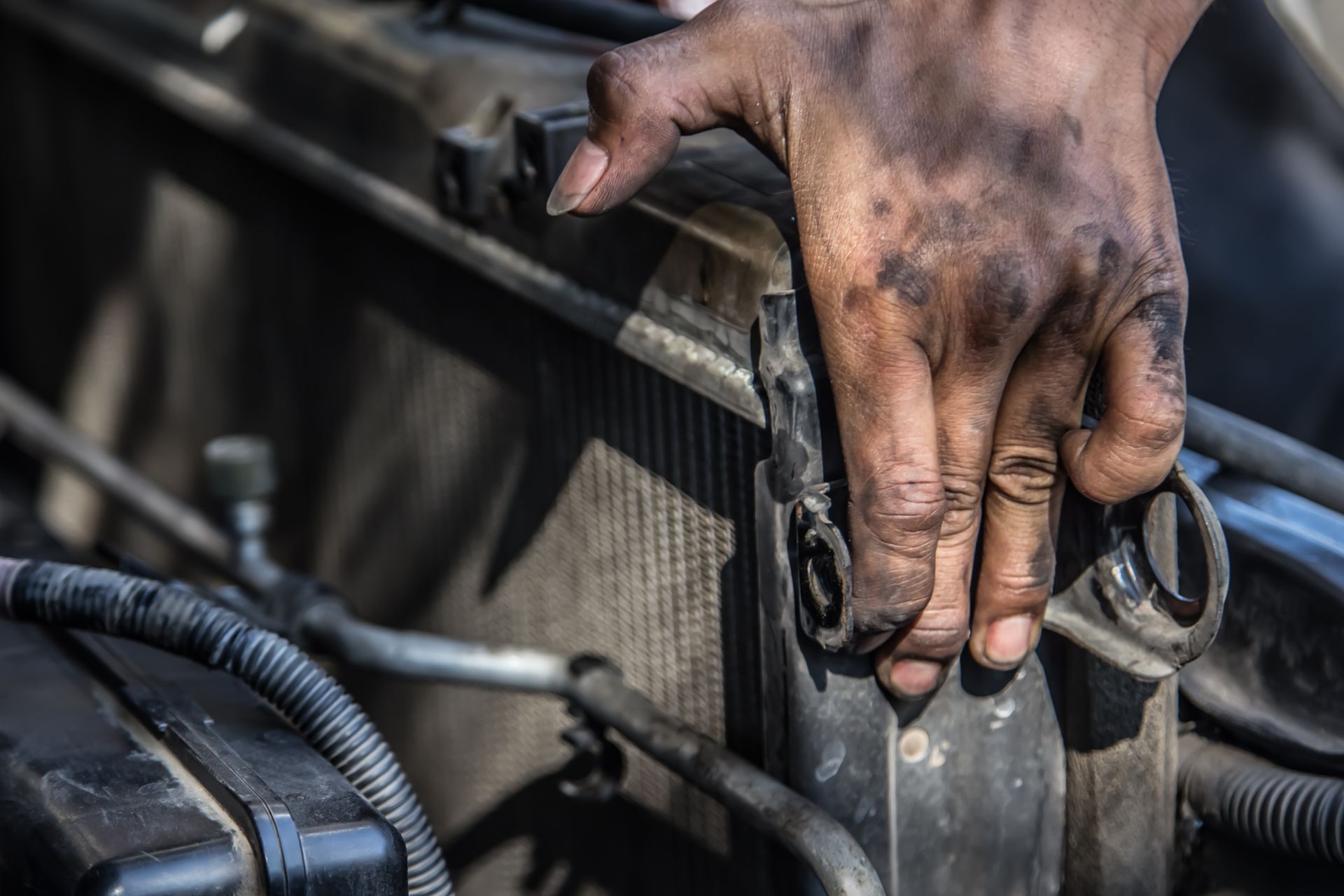 A dirty hand touching a car radiator