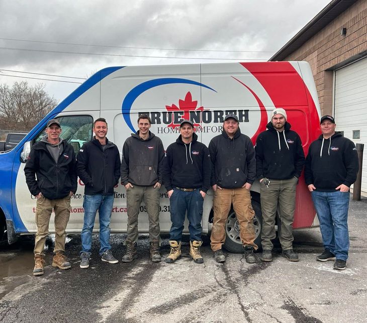 A group of men standing in front of a true north van