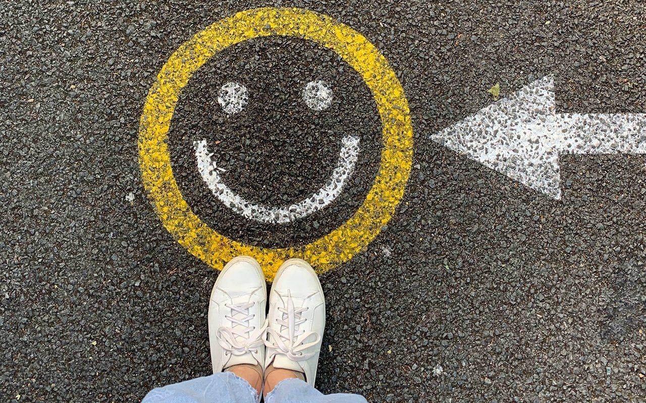 A person is standing next to a smiley face painted on the ground.