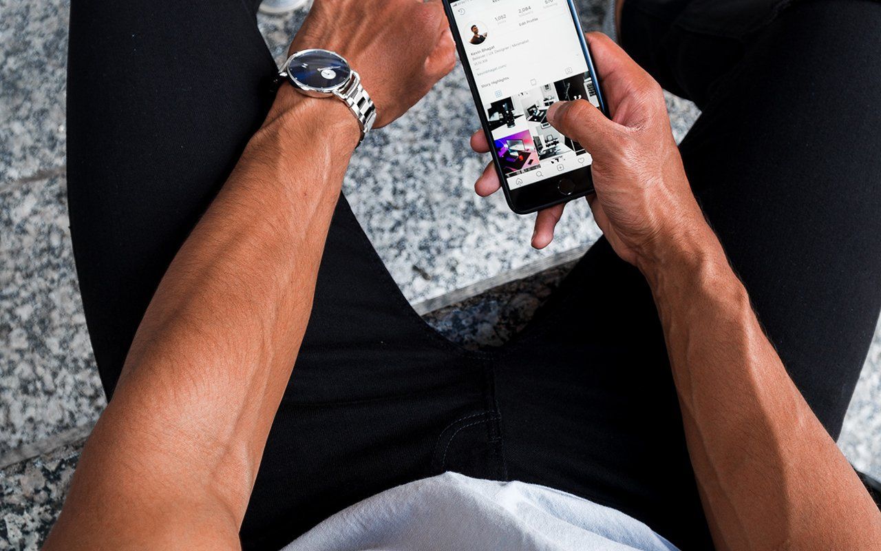 A man wearing a watch is using a cell phone.