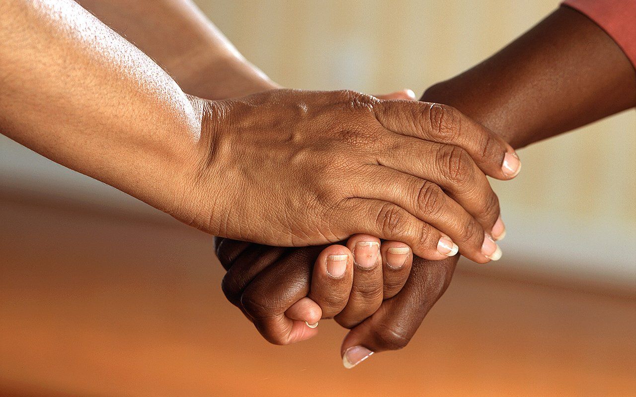 Two people are holding hands in a close up of their hands.