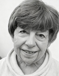 Close-up black-and-white portrait of a smiling person with short hair and a sweater