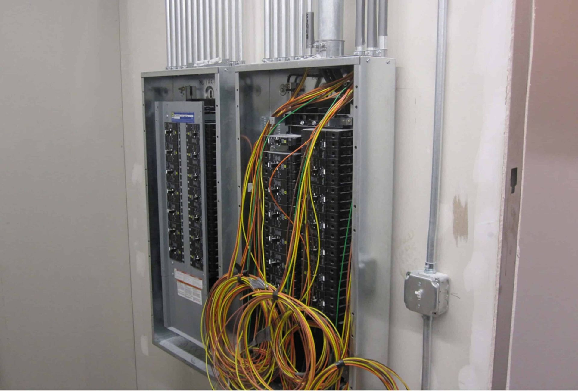 Open electrical cabinet with tangled yellow and black cables and network equipment in a wall recess