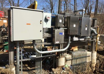 Outdoor industrial electrical equipment and control boxes on a metal platform among bare trees