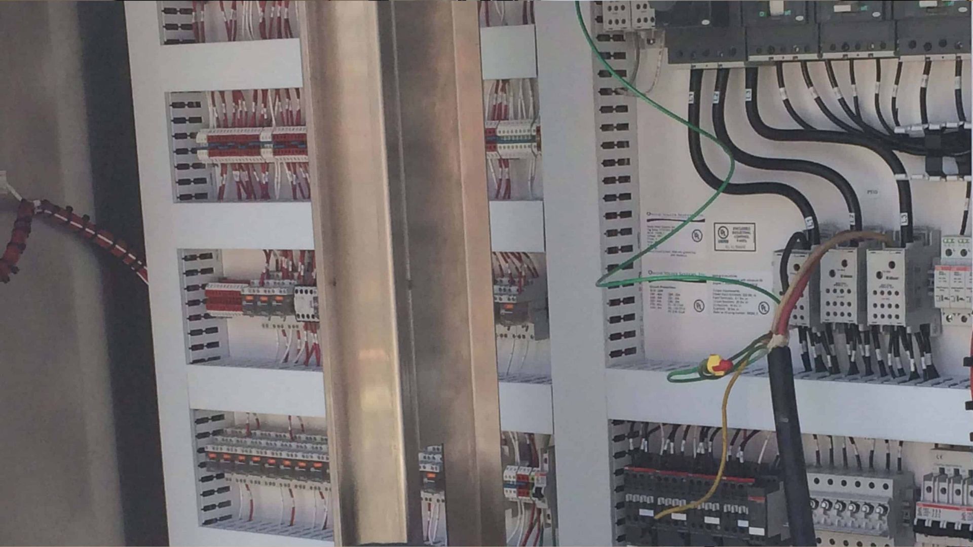 Electrical control panel with wiring, circuit breakers, and terminal blocks inside a metal cabinet