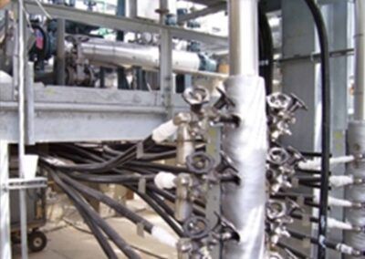 Industrial piping and valves in a metallic plant interior with bundled black cables