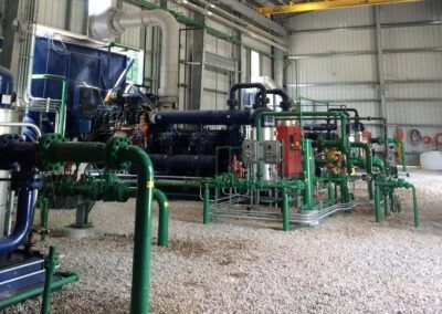 Industrial machinery with green pipes and tanks inside a factory hall