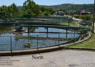 Circular water treatment tank with green railings in a landscaped park, labeled “North”