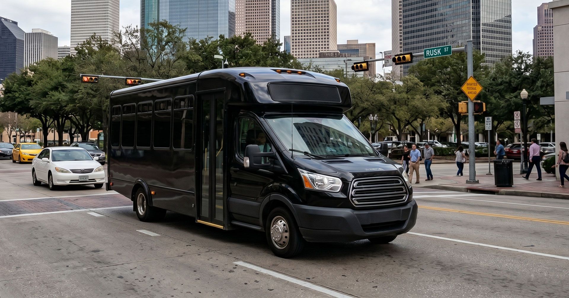 Black shuttle bus driving on a city street with tall buildings and pedestrians in the background