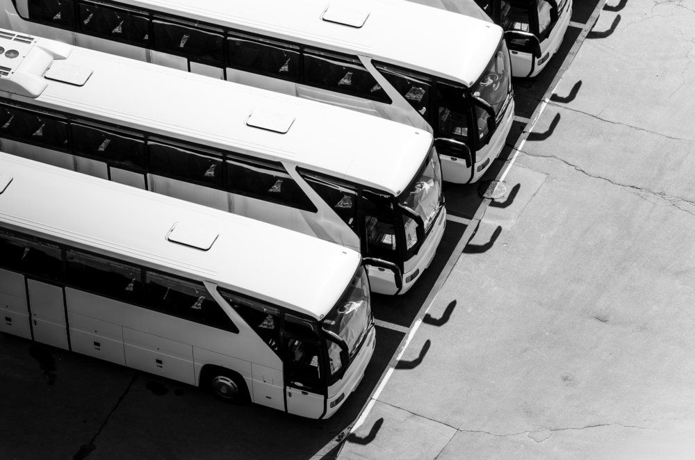 a black and white photo of a row of buses parked in a parking lot