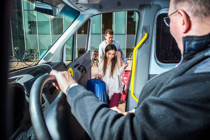 Bus driver helping passengers board at the front entrance