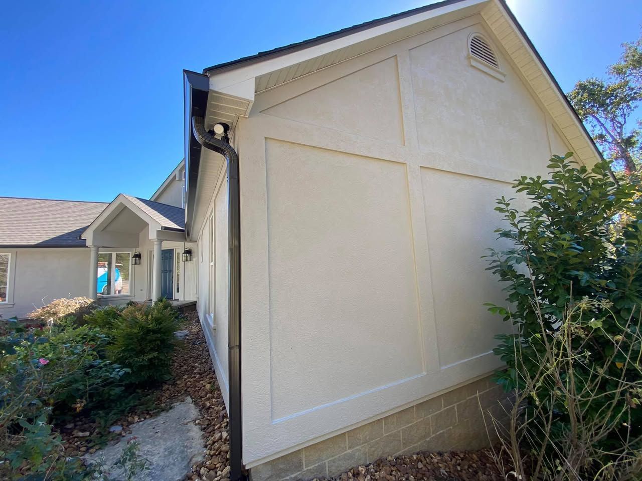 A white house with a black gutter on the side of it.