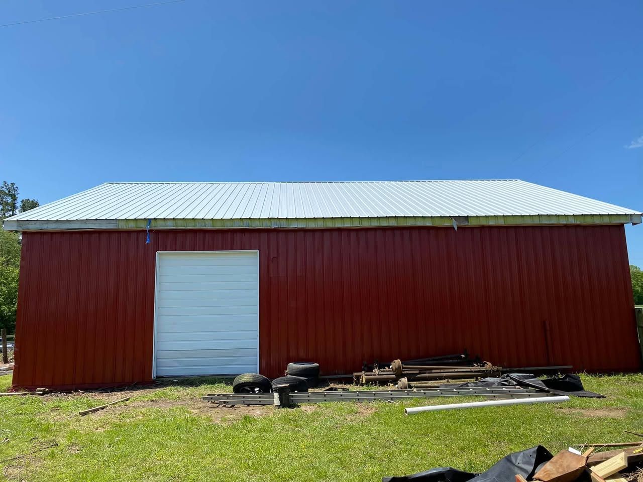 A red barn with a white garage door is sitting on top of a lush green field.