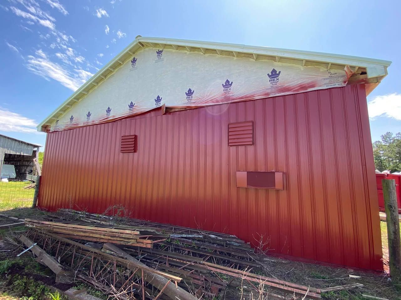 A red barn with a white roof is sitting in a field.
