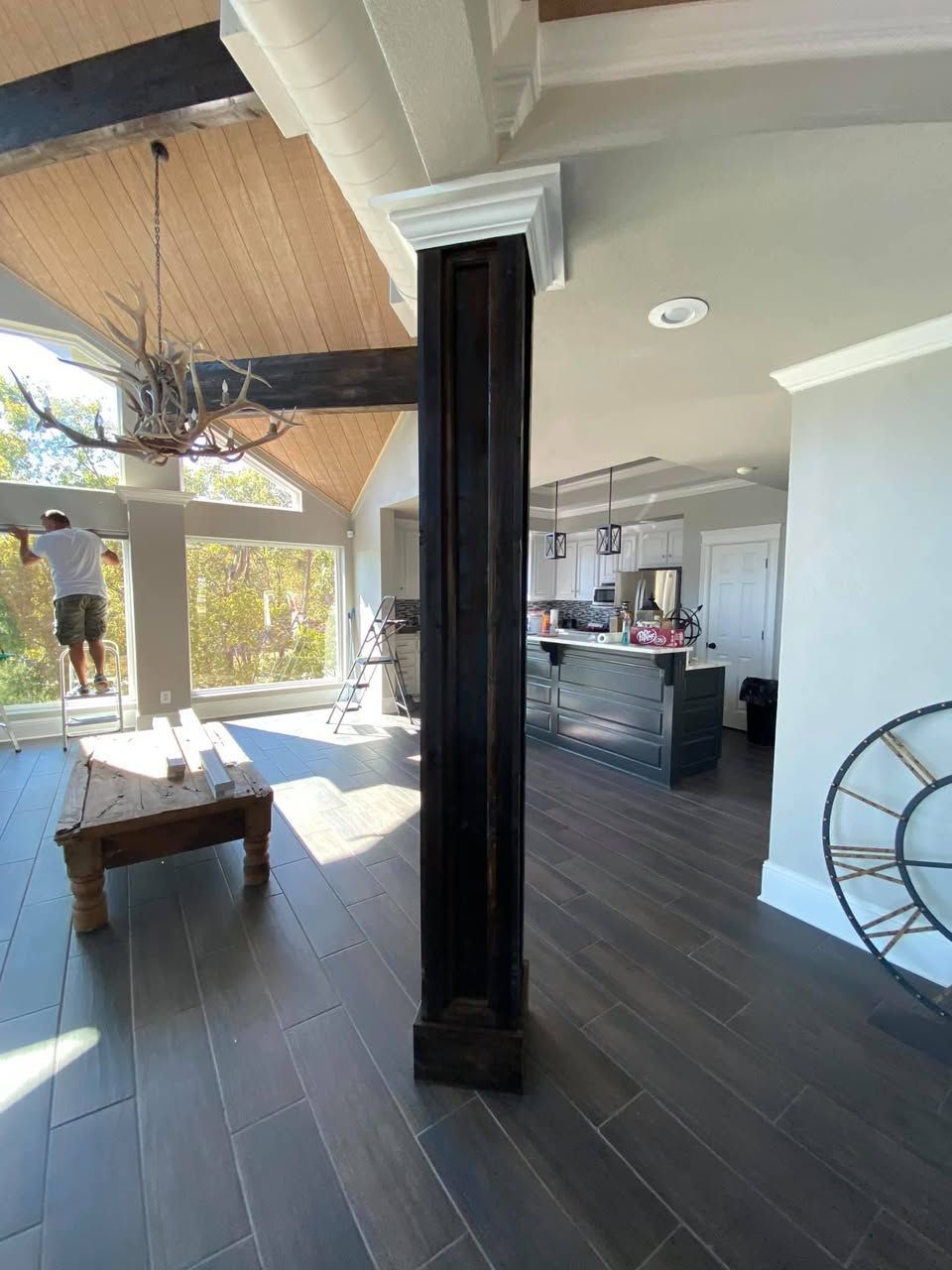A man is standing in a living room next to a clock.
