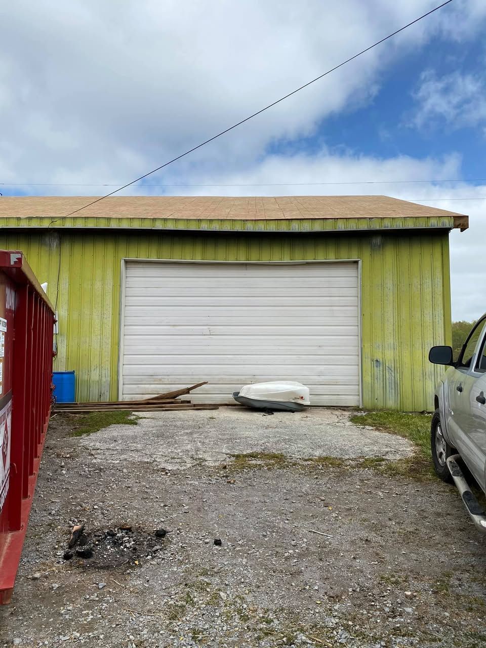 A truck is parked in front of a green building with a white garage door.