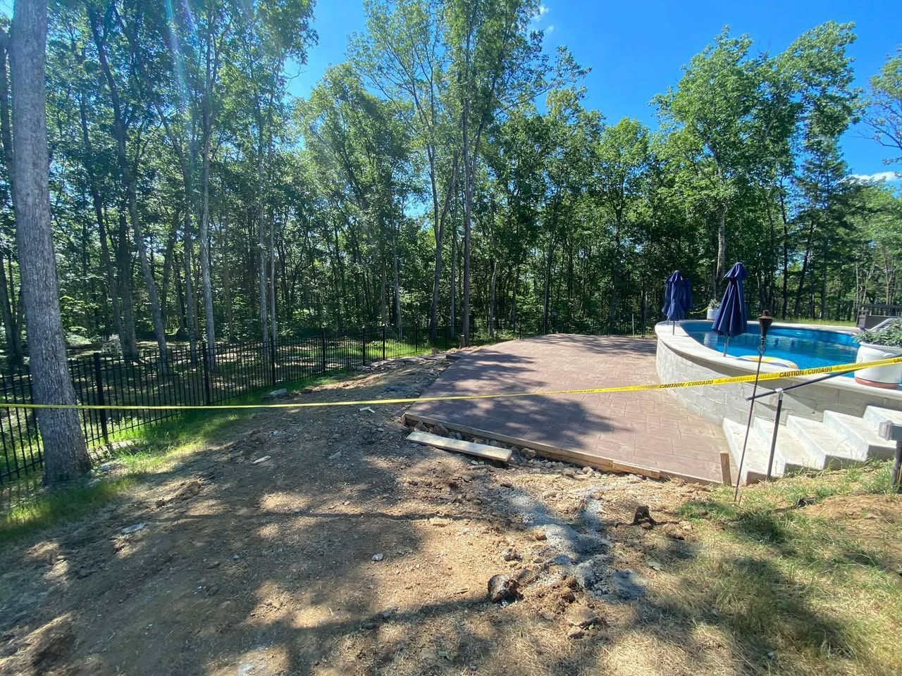 A swimming pool is being built in the backyard of a house surrounded by trees.