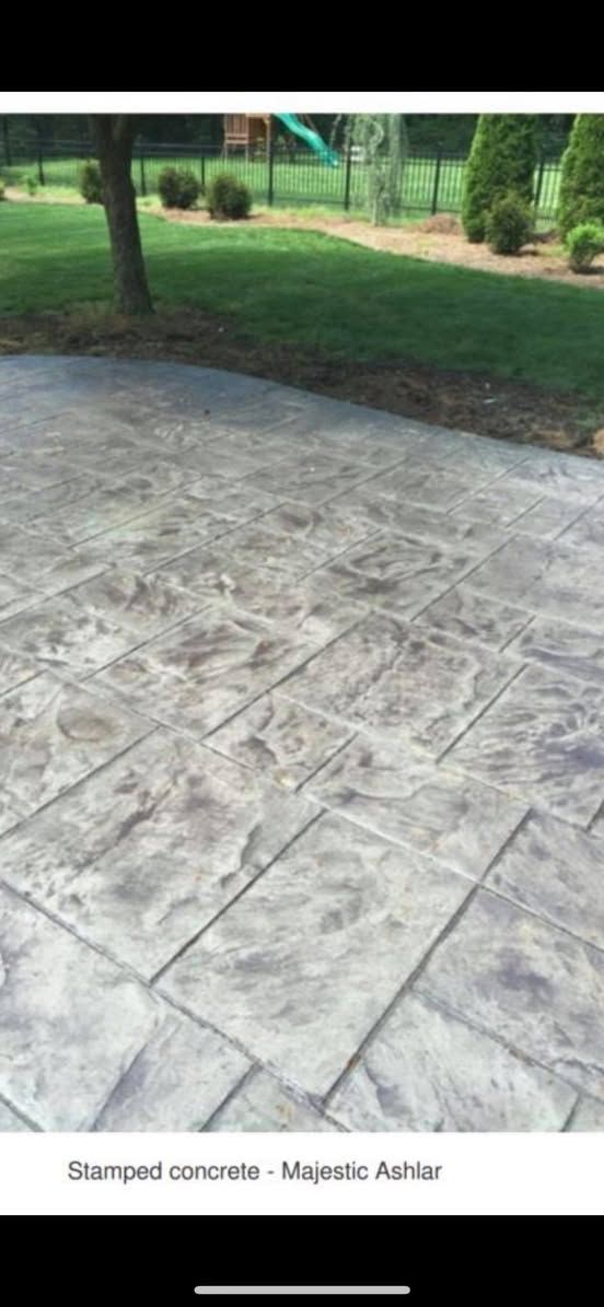 A picture of a concrete patio with a playground in the background.