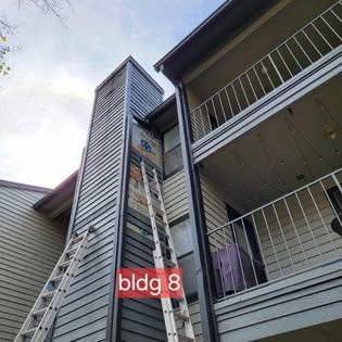 A ladder is sitting on the side of a building next to a chimney.