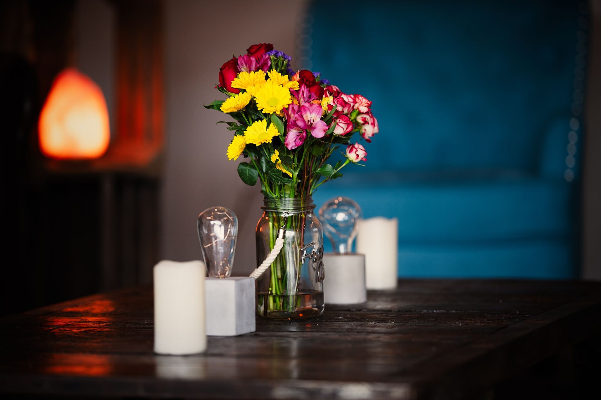 A table with a vase of flowers and candles on it.