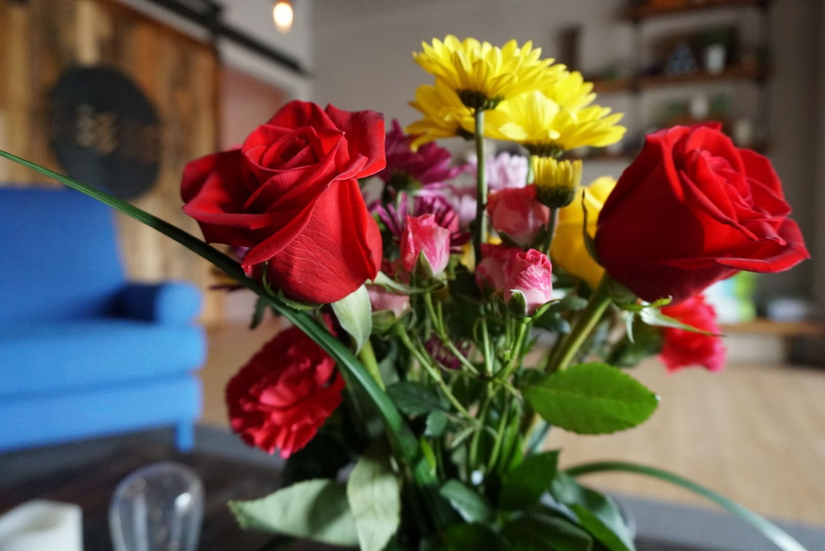 Red roses and yellow daisies in a vase on a table