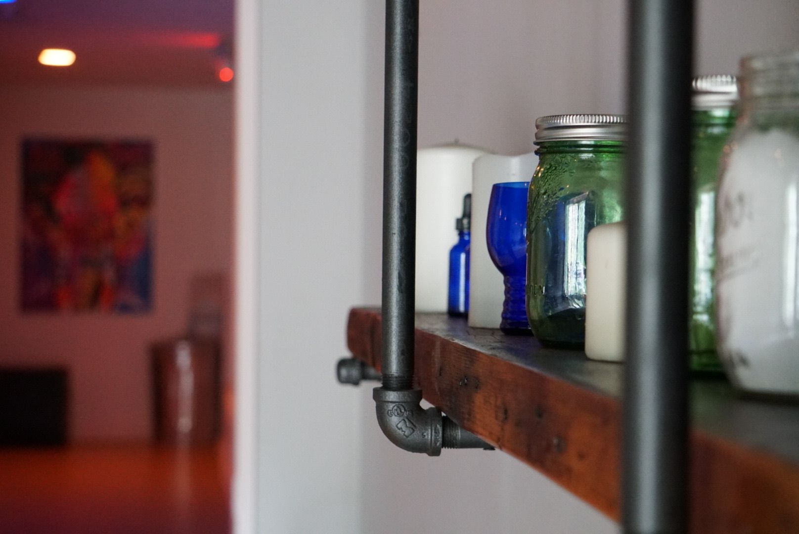 A shelf with candles and jars on it in a room.