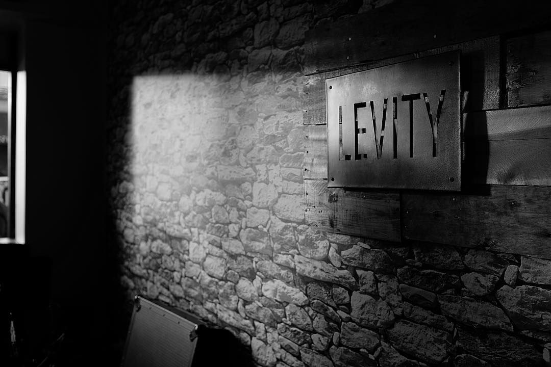 A black and white photo of a stone wall with a sign that says levity.