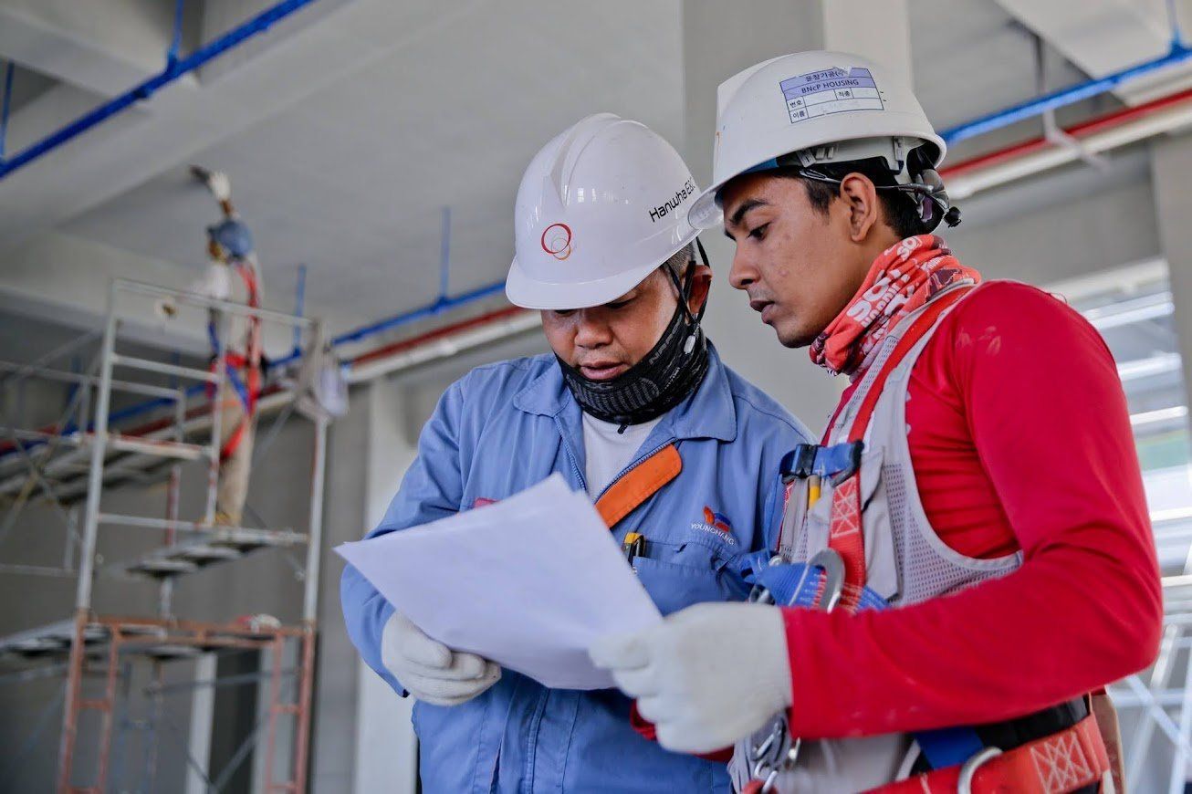 Two construction workers are looking at a piece of paper.