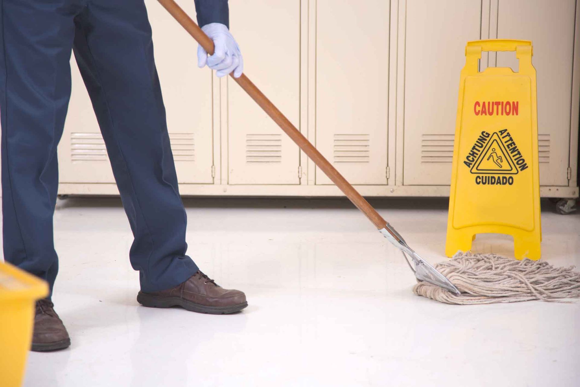 A man is mopping the floor next to a caution sign