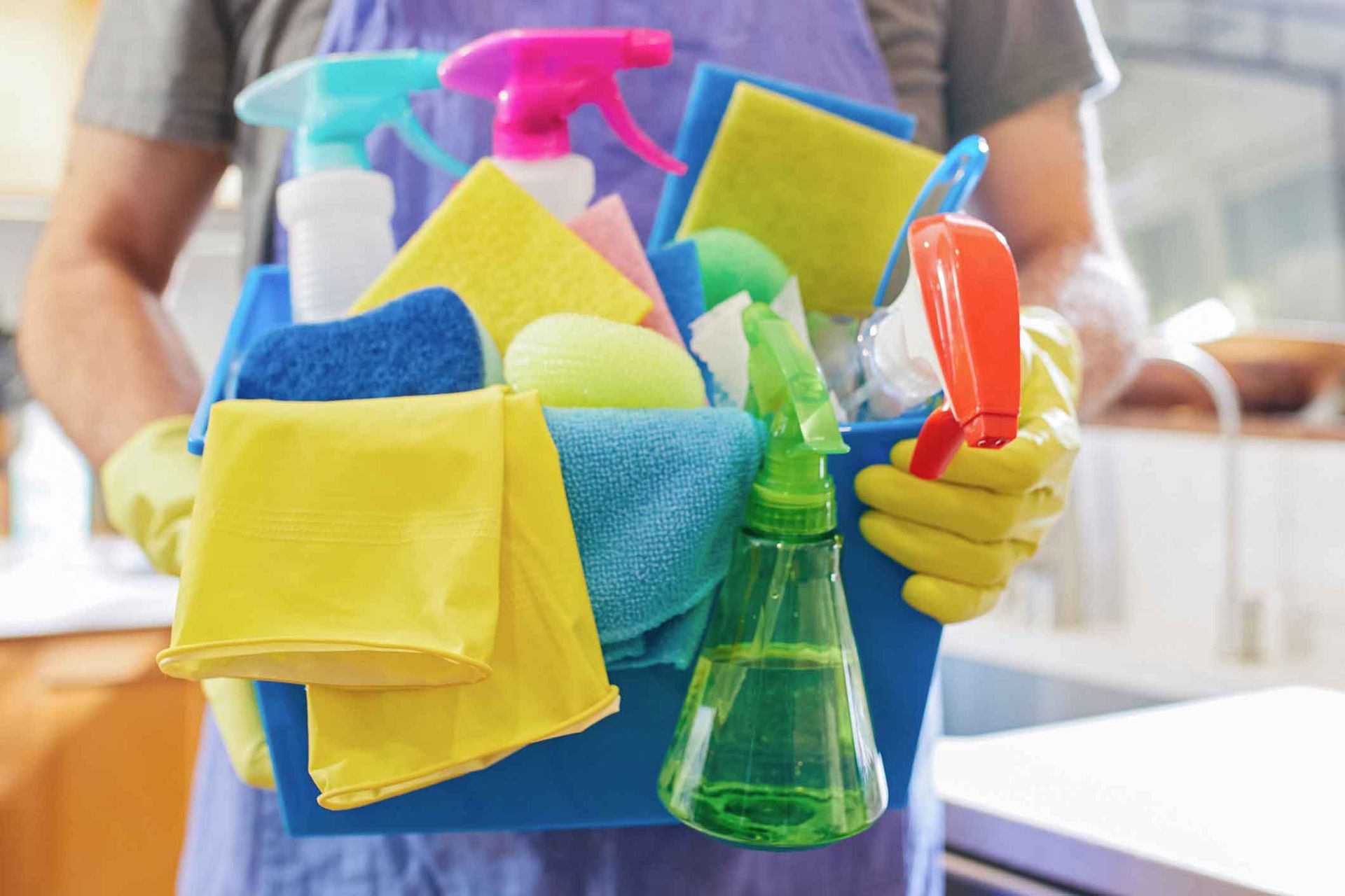 A person is holding a bucket full of cleaning supplies.