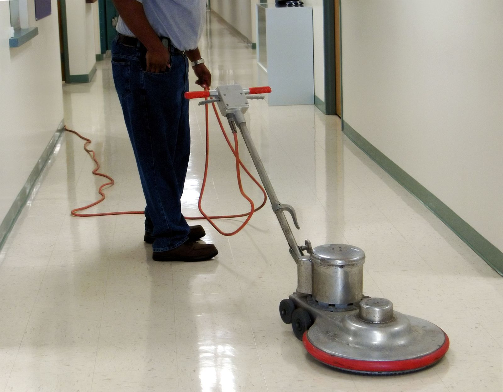 A man is using a machine to clean the floor in a hallway