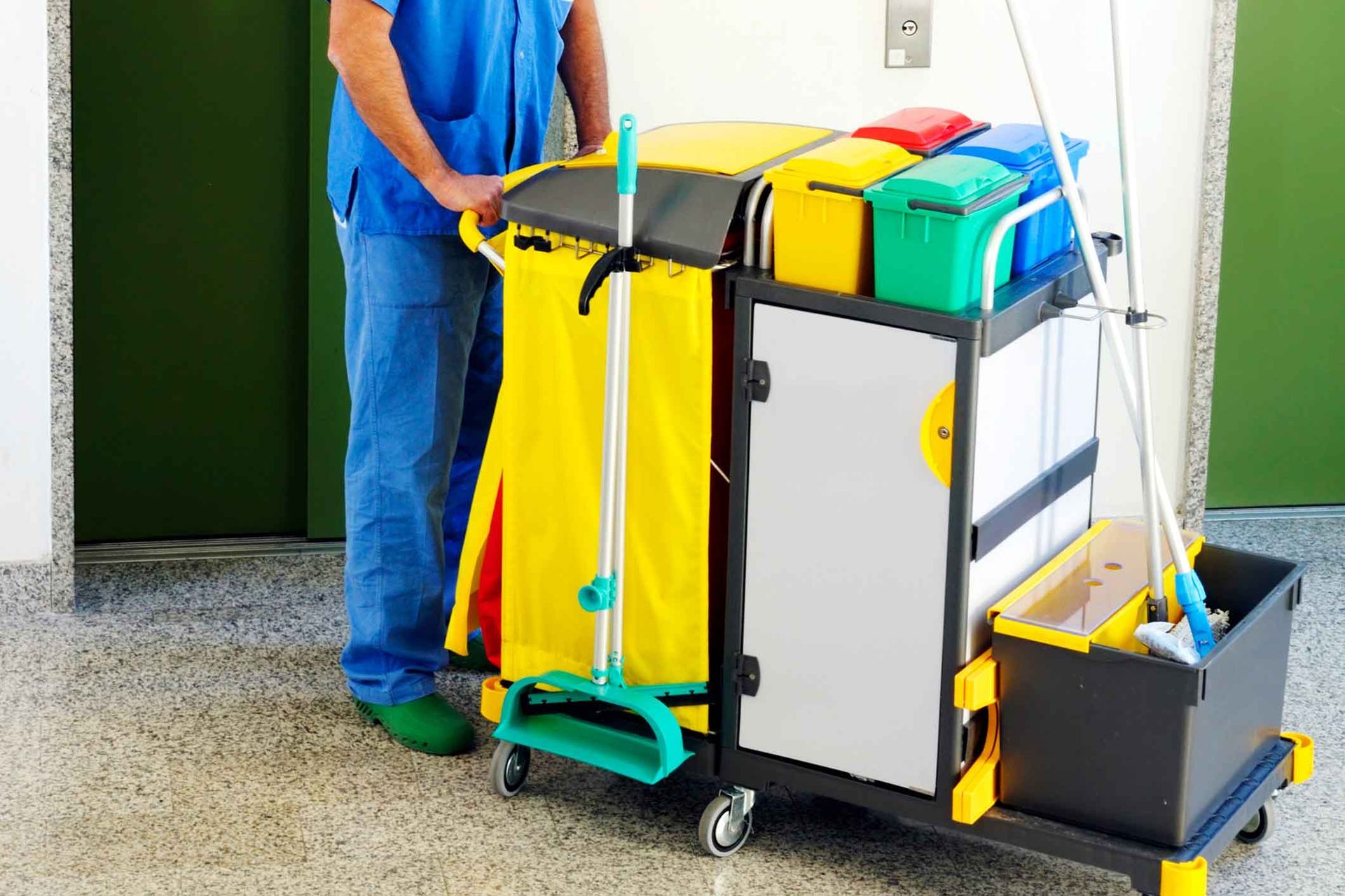 A man is standing next to a cleaning cart.