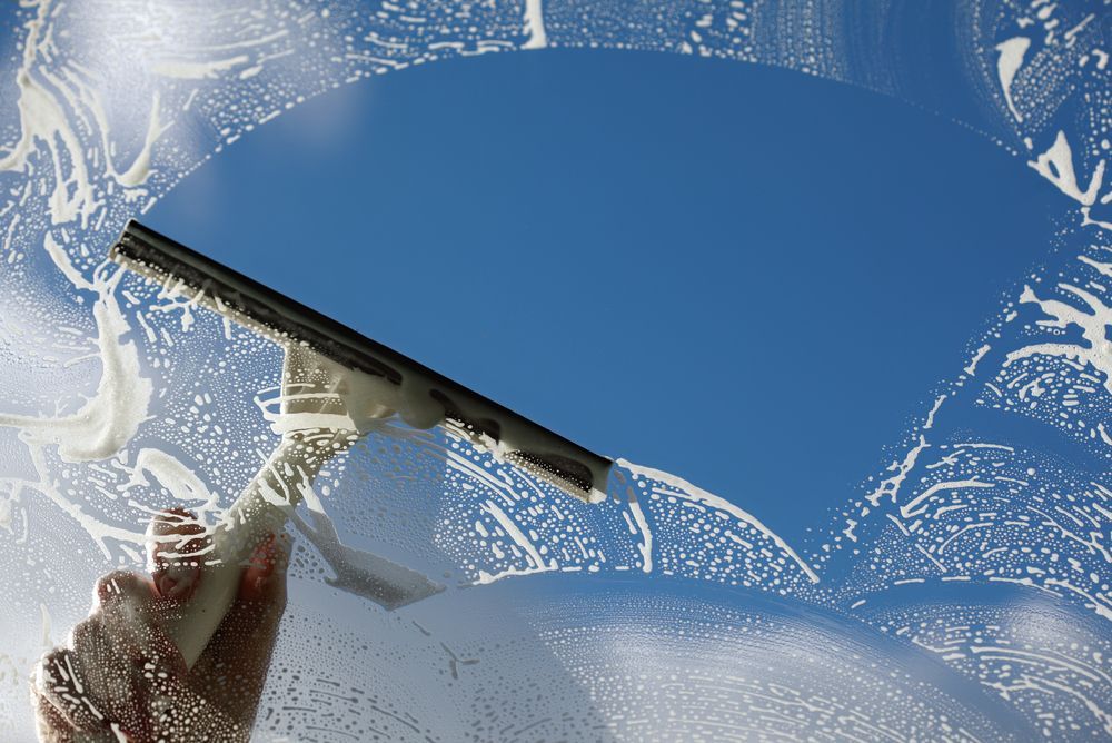 A person is cleaning a window with a squeegee.