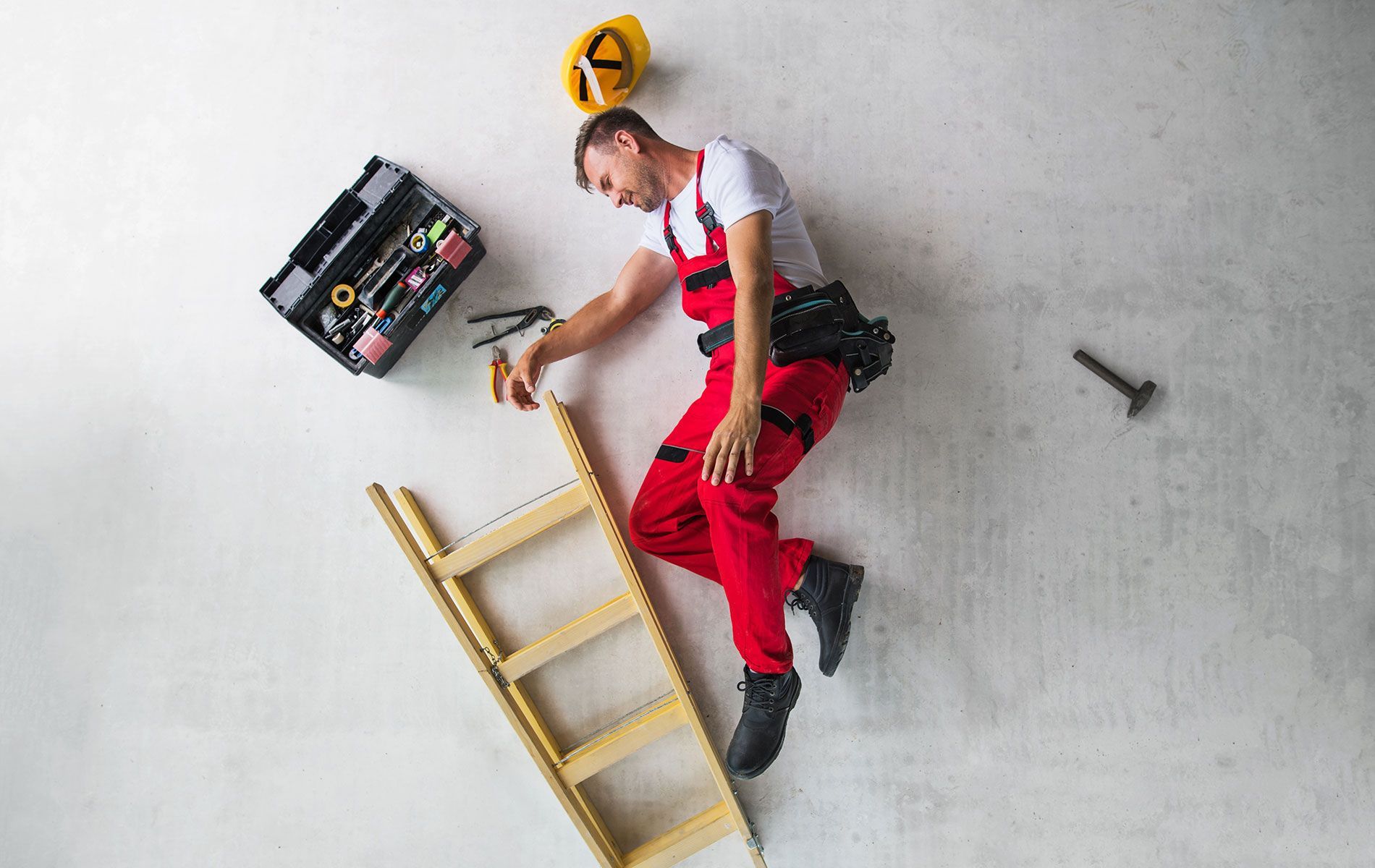 A man is laying on the floor next to a ladder.