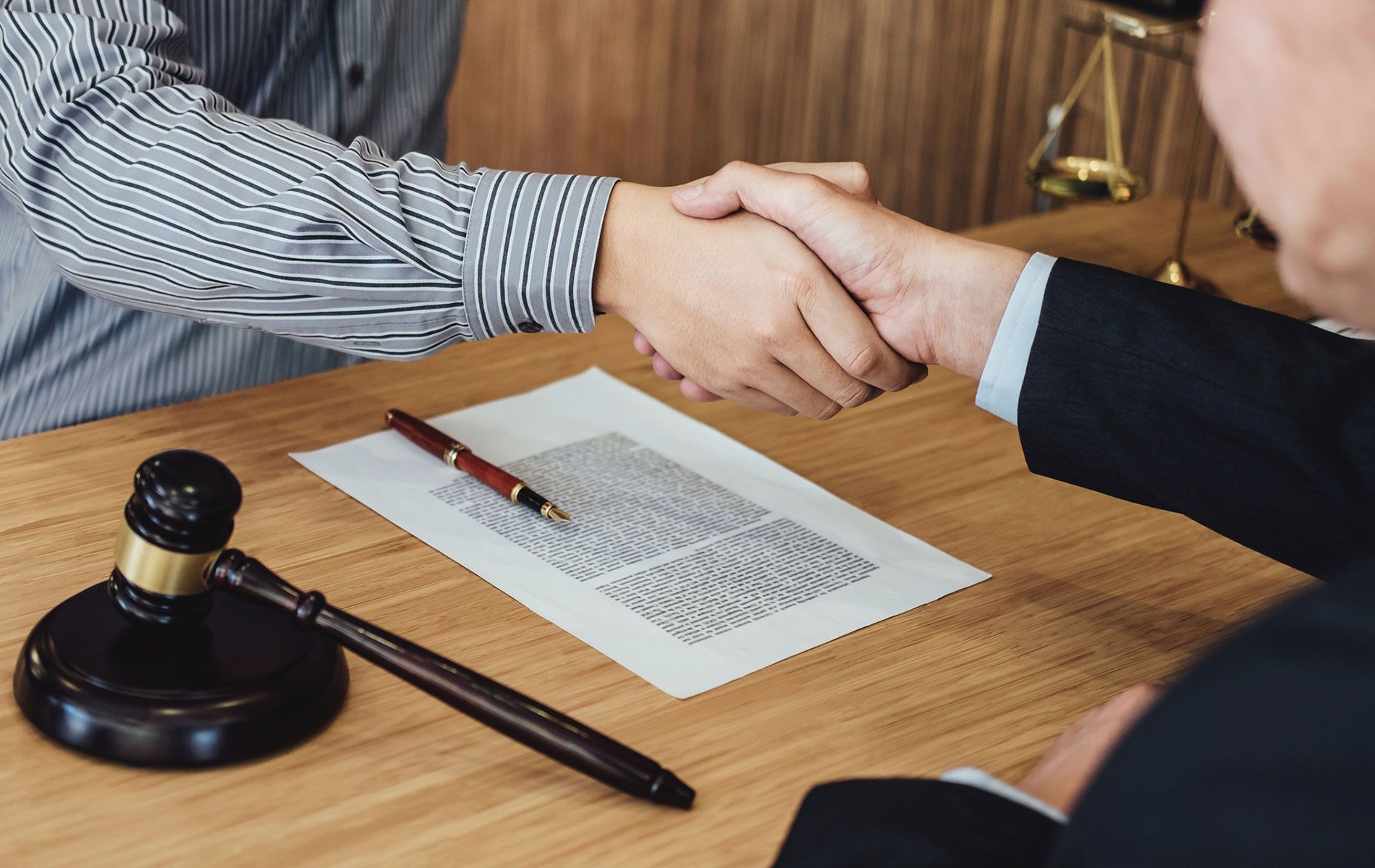 Two men are shaking hands over a piece of paper on a table.