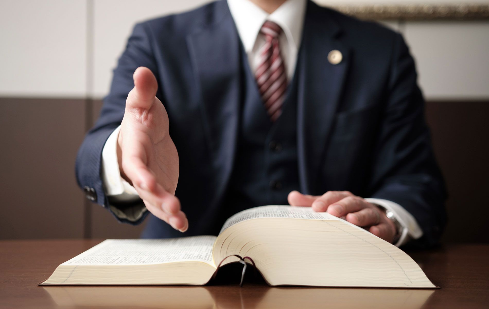 A man in a suit and tie is sitting at a table with an open book.