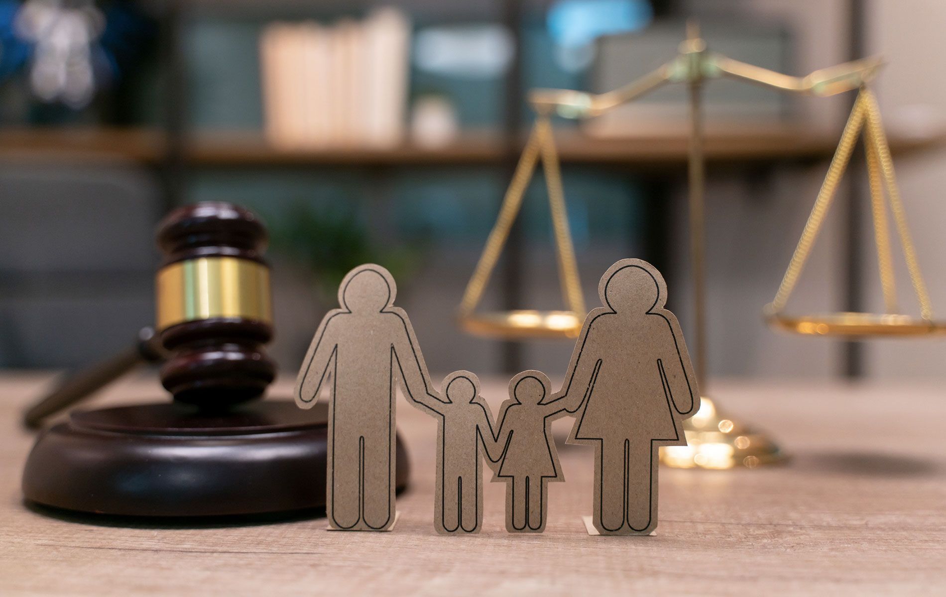 A wooden family standing next to a wooden gavel and scales of justice.