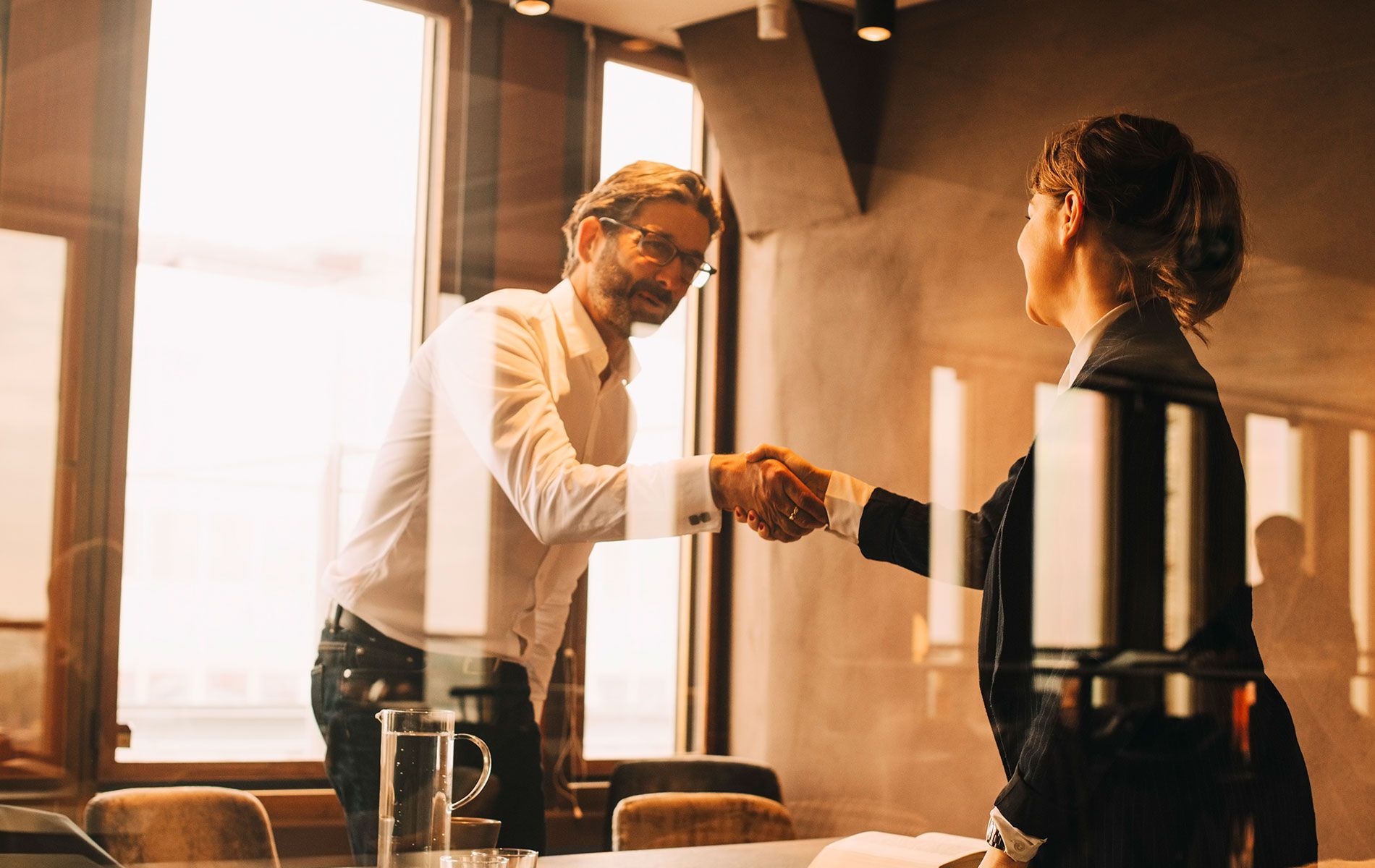 A man and a woman are shaking hands in a conference room.